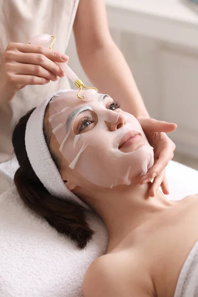Cosmetologist Massageando Rosto Mulher Com Máscara Folha Salão Close — Fotografia de Stock