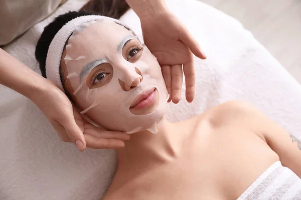 Kosmetolog Tillämpa Sheet Mask Unga Kvinnans Ansikte Salong Närbild — Stockfoto