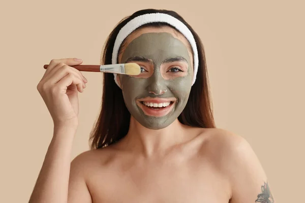 Jonge Vrouw Met Toegepaste Klei Masker Borstel Beige Achtergrond Close — Stockfoto
