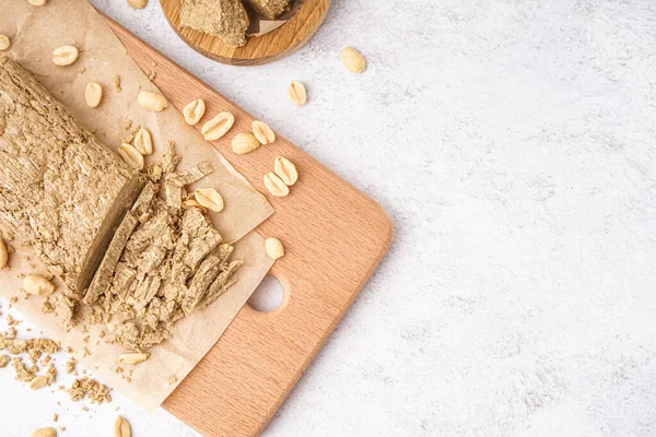 stock image Wooden board of sweet halva with peanuts on light background