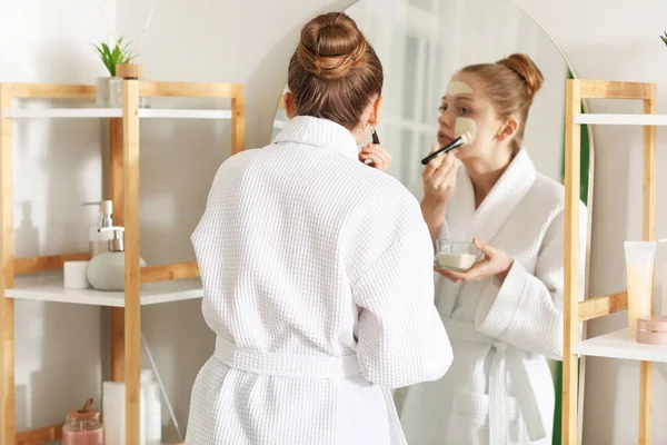 Νεαρή Γυναίκα Που Εφαρμόζει Κουρκουμά Μάσκα Πινέλο Κοντά Στον Καθρέφτη — Φωτογραφία Αρχείου