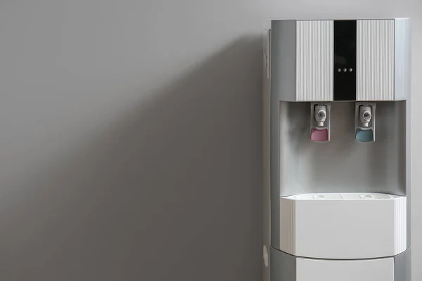 Modern water cooler on grey background