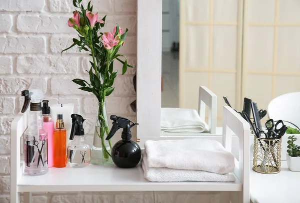 stock image Different hair sprays and towels on table in beauty salon