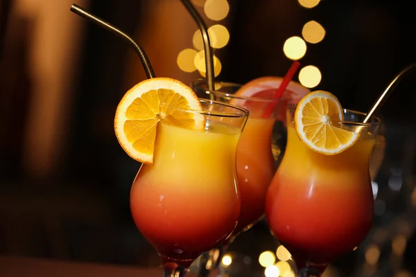 Glasses of tasty Tequila Sunrise with orange slices, closeup
