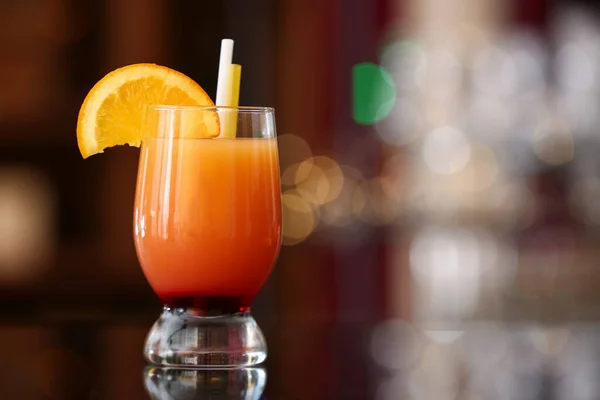 一杯美味的龙舌兰日出与橙片和稻草在酒吧的桌子上 — 图库照片