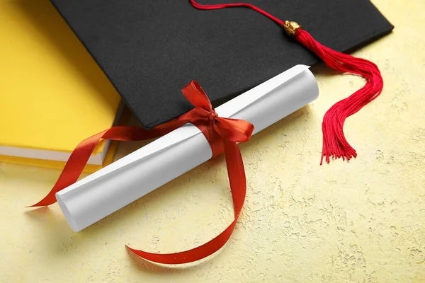 Kırmızı Kurdeleli Diploma Mezuniyet Şapkası Sarı Masadaki Kitap — Stok fotoğraf