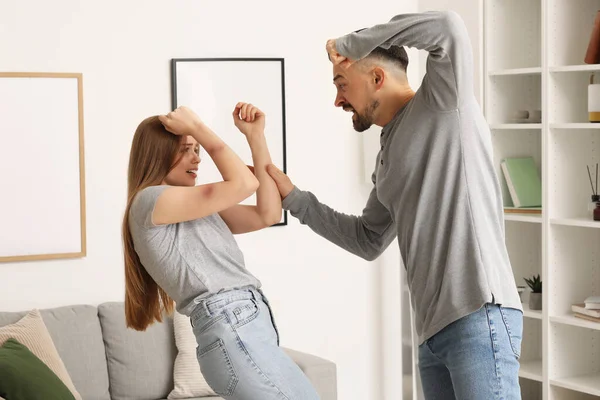stock image Bruised young woman and her angry husband at home. Domestic violence concept