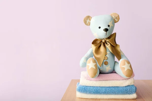 Speelgoedbeer Met Babykleertjes Tafel Nabij Lila Muur — Stockfoto