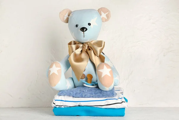 Speelgoedbeer Met Babykleertjes Fopspeen Tafel Bij Lichte Wand — Stockfoto