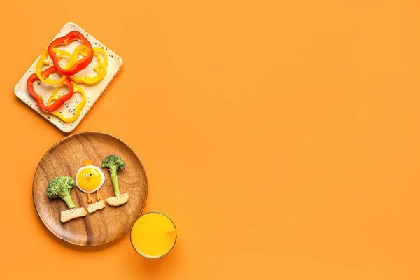 Plate with funny breakfast in shape of chick, bell pepper and glass of juice on orange background