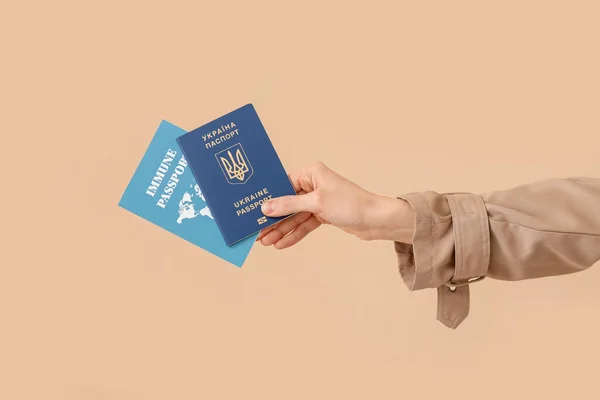持有乌克兰护照和米色背景豁免护照的妇女 — 图库照片
