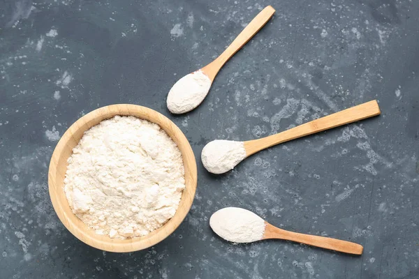 stock image Bowl and wooden spoons with wheat flour on grey grunge table