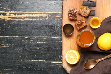 Tatlı ballı kavanoz ve koyu ahşap arka planda taraklar