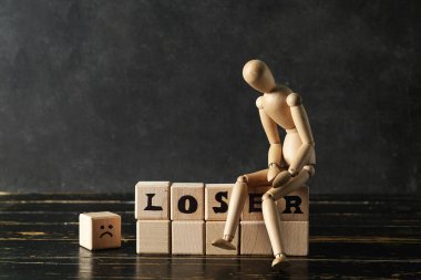 Karanlık duvarın yanındaki masada kelime ve manken içeren ahşap küpler.