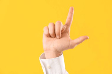 Genç işadamı sarı arka planda ezik jestleri gösteriyor