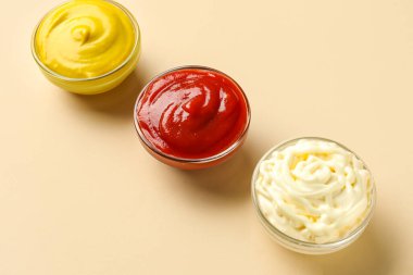 Bej arka planda ketçap, mayonez ve hardal kâseleri