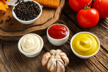 Farklı soslar ve ahşap masada sarımsak içeren kompozisyon.