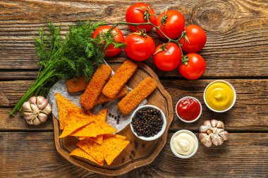 Farklı soslar, abur cuburlar ve ahşap masada sebzeler.