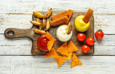 Farklı soslarla bezenmiş kompozisyon ve beyaz ahşap masada atıştırmalıklar