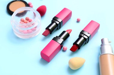 Mavi arka planda makyaj süngeri olan dekoratif kozmetik ürünleri