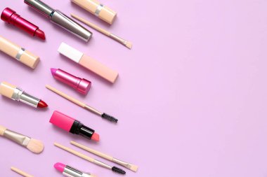 Eflatun arkaplanda makyaj fırçası olan dekoratif kozmetik ürünler.