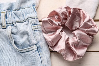Beyaz ahşap arka planda kot pantolonlu ipek toka, yakın plan