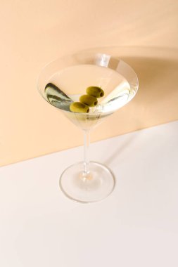 Bej arka planda zeytinli bir bardak martini.