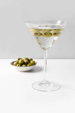 Hafif arkaplanda bir bardak martini ve zeytin.
