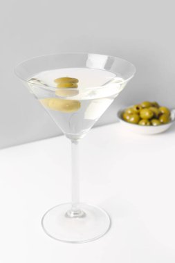 Hafif arkaplanda bir bardak martini ve zeytin.