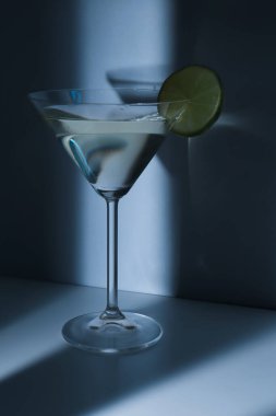 Mavi arka planda limonlu bir bardak martini.