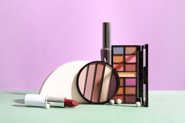 Dekoratif kozmetik ürünleri, leylak duvarın yanındaki masada.