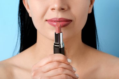 Mavi arka planda pembe rujlu kadın, yakın plan.