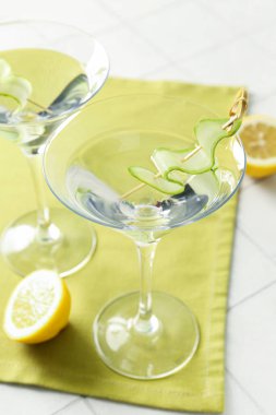 Beyaz fayans masasında bir bardak lezzetli martini ve limon.