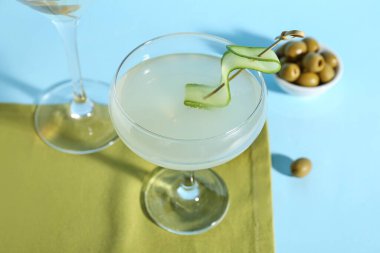 Bir bardak lezzetli martini ve açık mavi arka planda zeytinler.