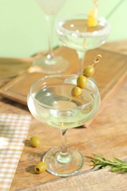 Tahta masada bir bardak lezzetli martini ve zeytin.