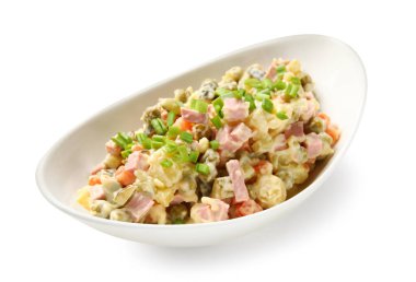 Beyaz arka planda bir kase lezzetli Olivier salatası.