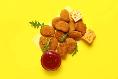 Sarı arka planda peynirli ve ketçaplı bir yığın lezzetli nugget.