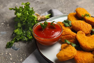 Arkaplanda ketçap bulunan lezzetli nugget tabağı, yakın plan.