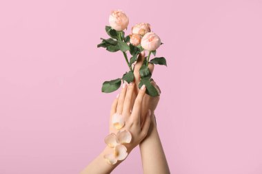 Pembe arka planda gülleri olan bir kadın. El bakımı kavramı
