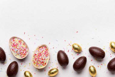 Çikolatalı Paskalya yumurtası ve beyaz arka planda serpiştirilmiş çikolata.