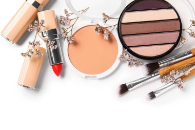 Beyaz arkaplanda fırça ve çiçeklerle dekoratif kozmetik ürünler