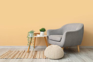 Oturma odasının içinde, koltuğu ve yapay bitkileri olan bir masa.