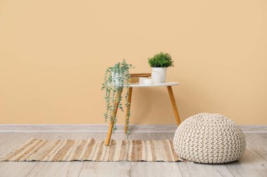 Oturma odasındaki masada kitap ve mumlarla suni bitkiler.