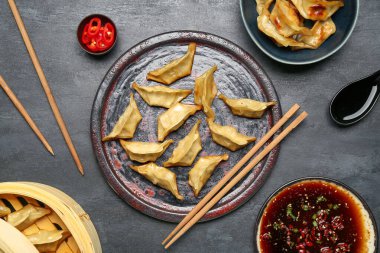 Lezzetli Çin jiaozi tabağı, bambu buharı ve siyah arka planda sos.