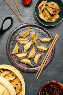 Lezzetli Çin jiaozi tabağı, bambu buharı ve siyah arka planda sos.