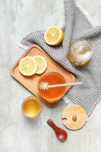 Jars of sweet honey and lemon on grey background