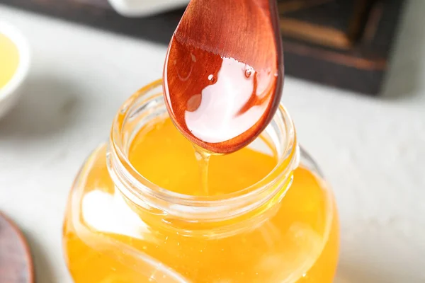 軽い背景にスプーンから瓶に甘い蜂蜜の注ぎ クローズアップ — ストック写真