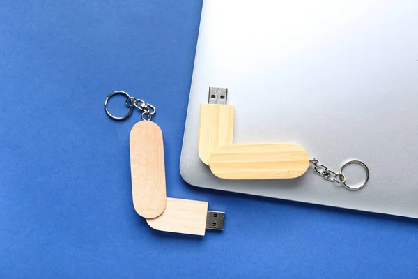 Wooden USB flash drives and modern laptop on blue background