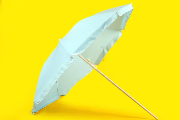黄色の背景に青いビーチの傘 — ストック写真