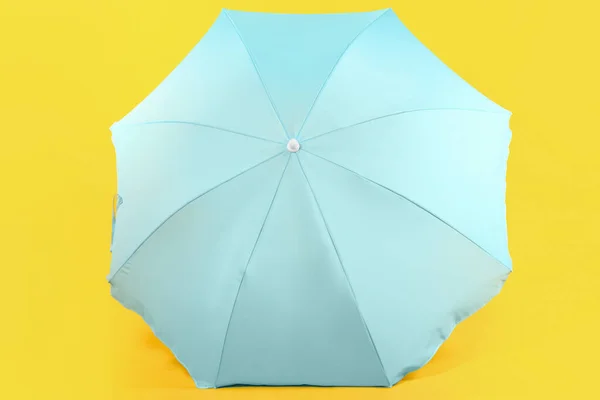黄色の背景に青いビーチの傘 — ストック写真